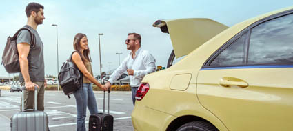 Summer sale on airport transfers from Lymm and Warrington with Arrivals Star Taxis driver helping passengers with suitcases into a car